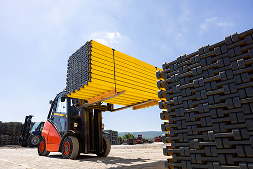 image of a forklift carrying large stack of materials for all-terrain forklifts vs forklifts hire