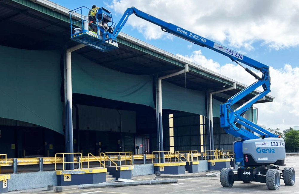 Image shows a knuckle boom lift from hired from AAH Australia with maintenance workers working at height on a buildings gutters and roof