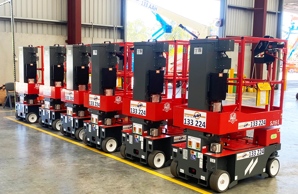 Image shows a fleet of electric vertical lifts in a line in a warehouse environment ready to be hired from AAH